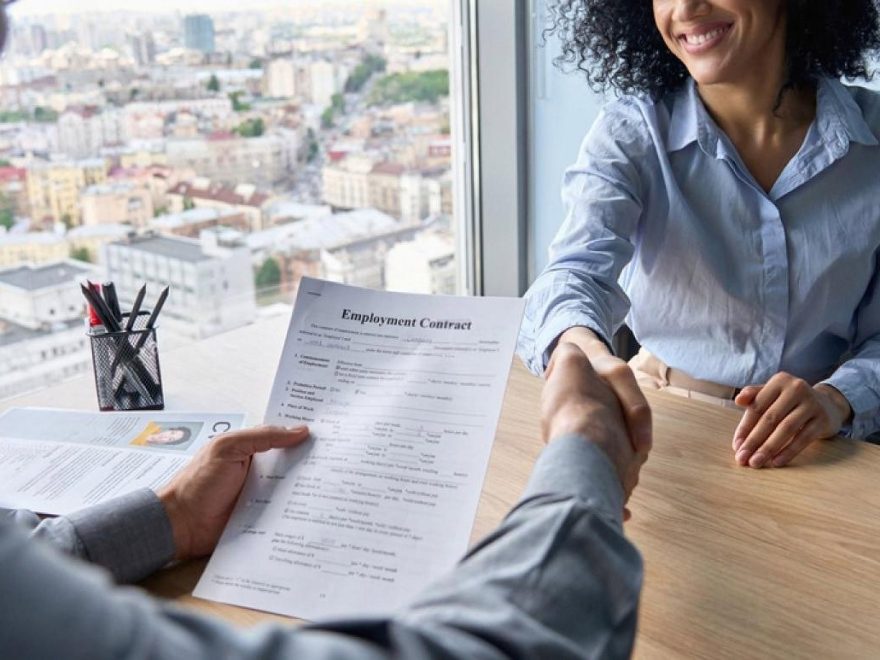 HR consultant and candidate signing an employment contract with a Dubai city view